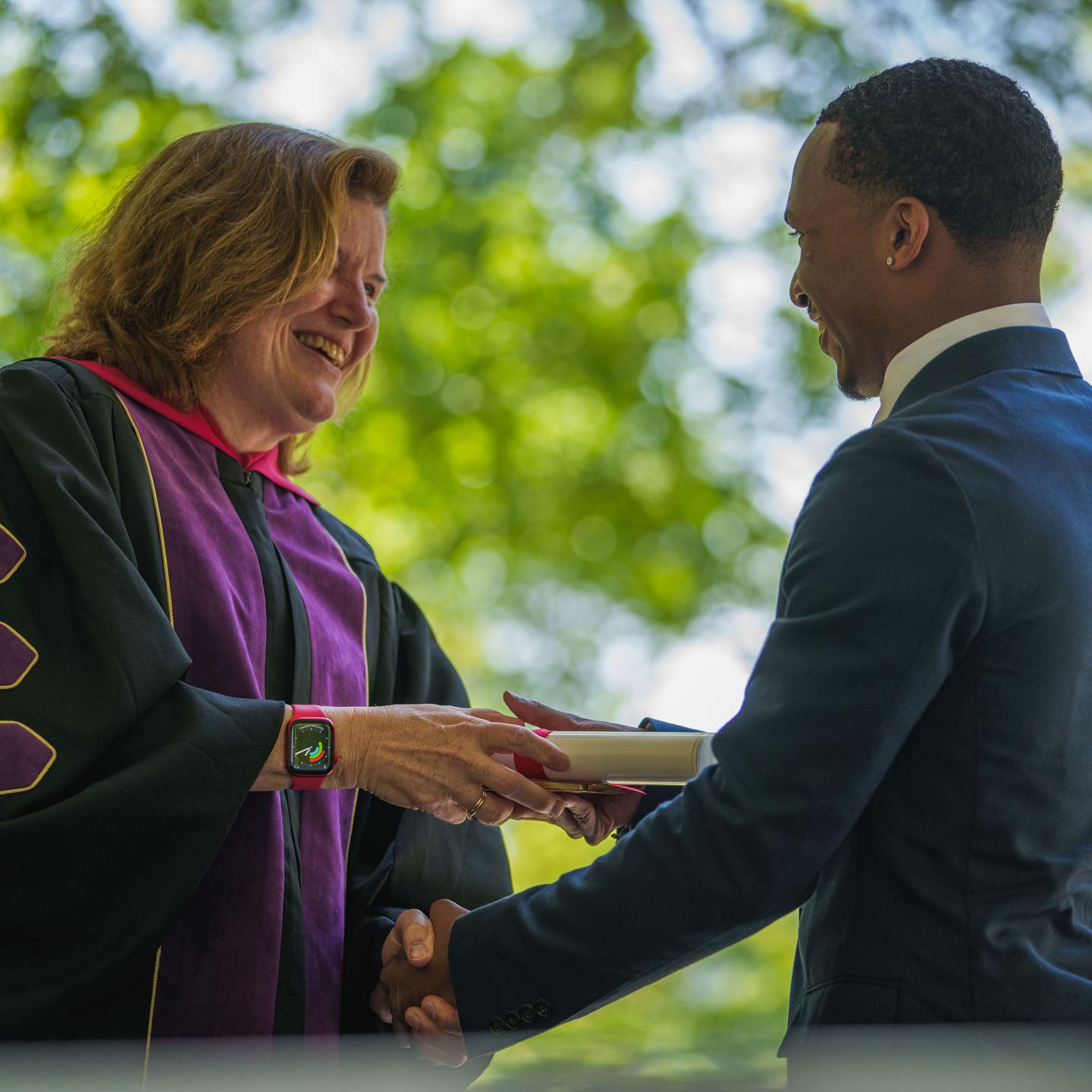 Rector Kathy Giles awarding diploma to Cris Ramirez