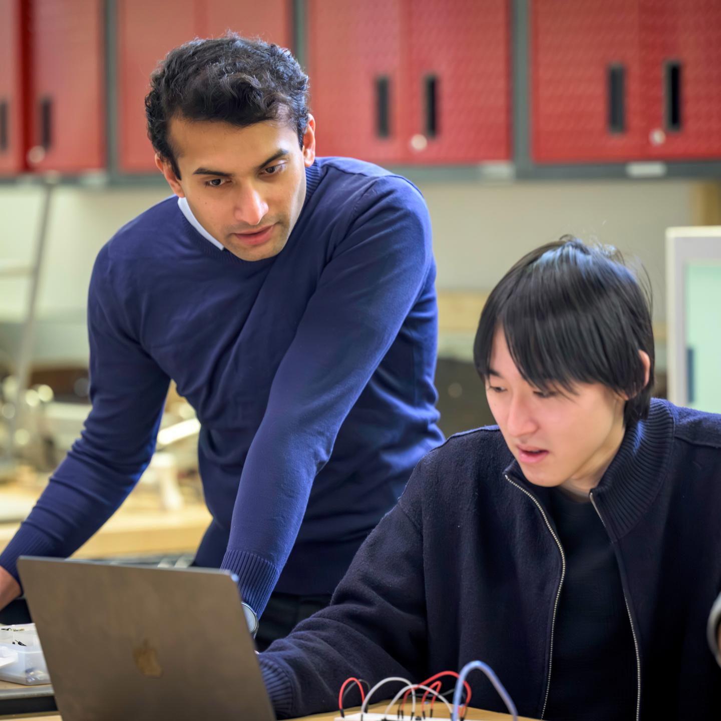 Computer Science teacher Shreyas Rane reviews lines of code with a student.