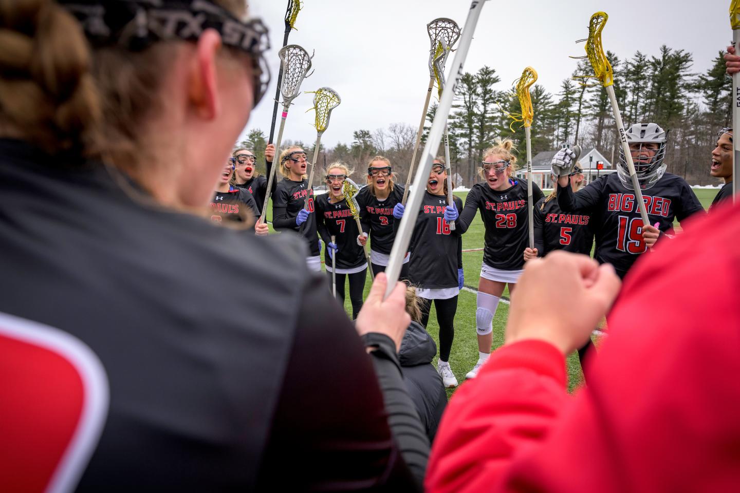 girls varsity lacrosse huddle before their game against Exeter.